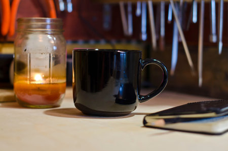 A tool bench with a blank black coffee mug at planner.