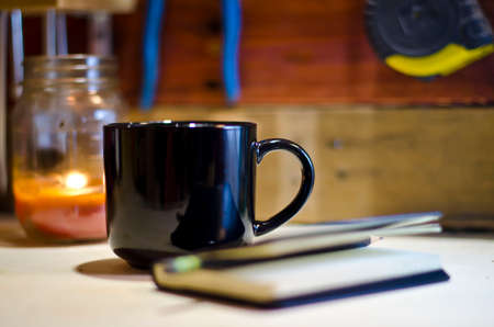A blank black mug on a tool bench writing out the morning tasks.の写真素材
