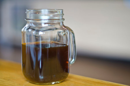 a half full dark coffee in a mason jar on the table of the local coffee shop.の写真素材