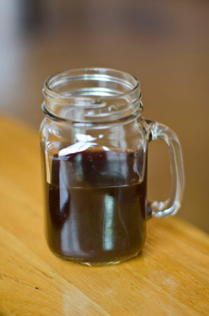 A single dar coffee in a mason jar mug on the table of the local coffee shop.