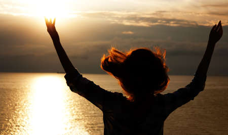 Silhouette of a Woman Praying at Sunsetの写真素材