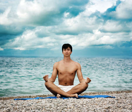 Young Man Practicing Yoga near the Oceanの写真素材