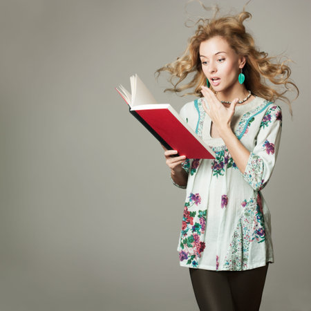 Surprised Blonde Woman Reading a Book on Gray Background  Copy Space 