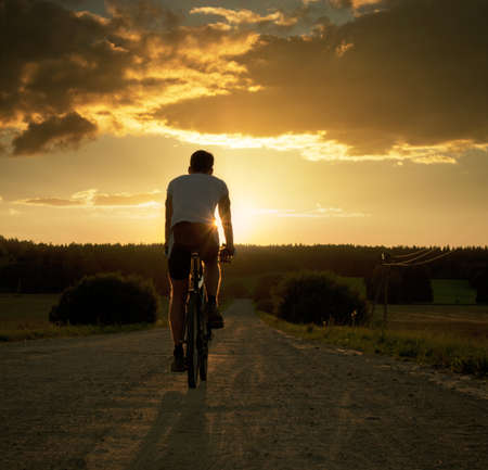 Rear View of a Young Man Riding a Bicycle at Sunset  Healthy Lifestyle Concept  Copyspace の写真素材