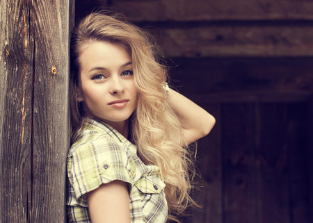 Toned Portrait of Beautiful Blonde Woman on Wooden Backgroundの写真素材