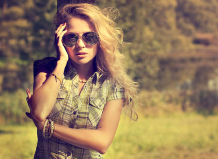 Trendy Hipster Girl in Sunglasses Touching Her Face. Summer Modern Youth Lifestyle. Toned Photo.の写真素材