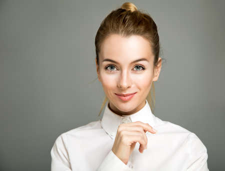 Portrait of Smiling Business Woman Wearing White Shirt against Gray Backgroundの写真素材