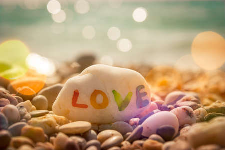 Stone with LOVE text on Sea Background. Filtered Photo with Bokeh. Romantic Travel Concept.の写真素材