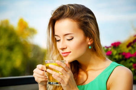 Young Woman Drinking Green Tea Outdoors. Summer Background. Shallow Depth of Field.の写真素材