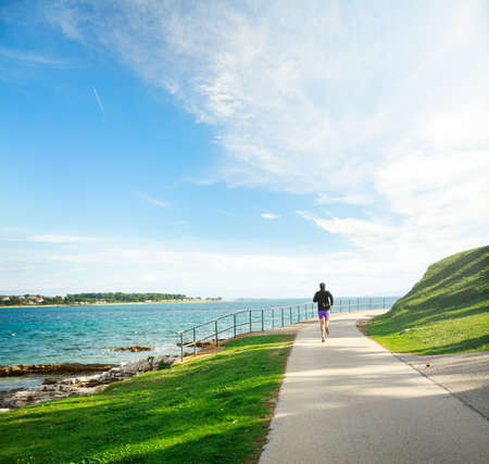 Man Running on the Sea Coast. Sport and Jogging on Beautiful Nature Background Concept. Toned Photo with Copy Space.の写真素材