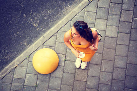 Young Fashion Woman with Coffee to Go in the City. Casual Summer Street Style. Top View. Toned and Filtered Photo with Copy Space.の写真素材