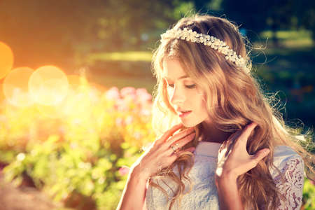 Charming Bride with Wedding Tiara on Warm Nature Background. Modern Bridal Style. Candid Image. Toned Photo with Bokeh and Copy Space.の写真素材