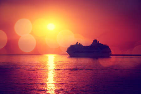 Silhouette of Cruise Ship at Sea Sunset Background. Romantic and Luxury Travel Concept. Toned and Filtered Photo with Bokeh. Copy Space.の写真素材