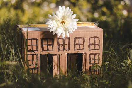 model of cardboard house with a bow of twine and key against green bokeh background. house building, loan, real estate or buying a new home concept.の写真素材