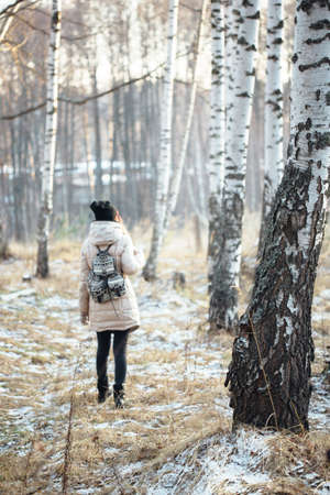 Woman with small backpack walking alone in snowy winter forestの写真素材