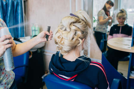 Hair stylist working on haircut for beautiful girl. Focus on the womanの写真素材
