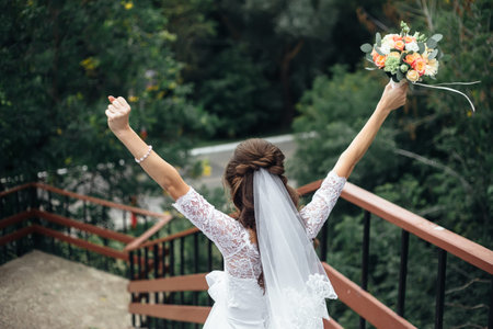 bride with hands up and a bouquet