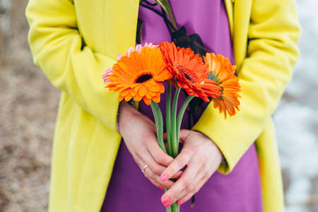 girl holds flowers, bright colors background yellow, orange, purpleの写真素材