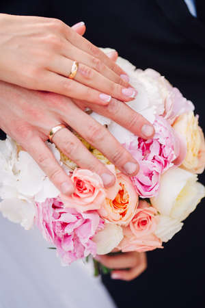 Hands and rings on wedding bouquet togetherの写真素材
