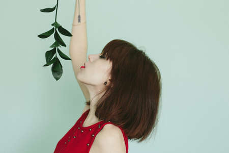 girl in red dress with green banch Add noise and filters.の写真素材