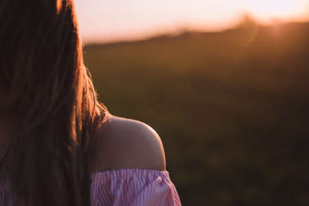 Beautiful young woman sitting in a meadow with a bouquet of lavender and dreaming in the sunset raysの写真素材