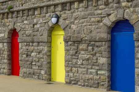 Three colored doors set into a stone wall - red, yellow, blueの写真素材