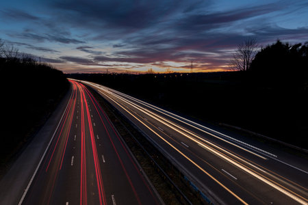 A UK motorway, at sunset, with light trails created by the traffic on the road