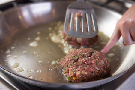 Placing Organic Hamburger Patties With Spatula in a Pan With Butter