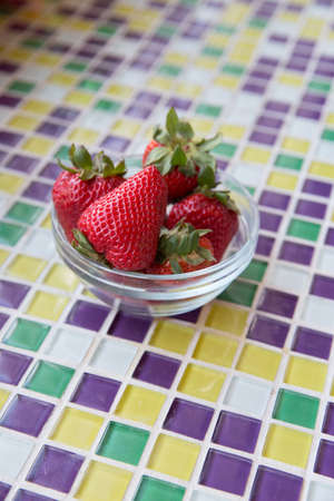 Fresh Strawberries in a Clear Bowl with Mosaic Tilesの写真素材