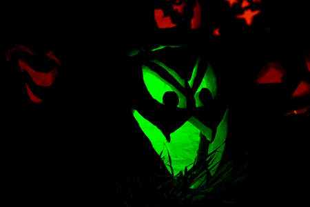 Jack-O-Lanterns Carved for Halloween Lit in Orange and Greenの写真素材