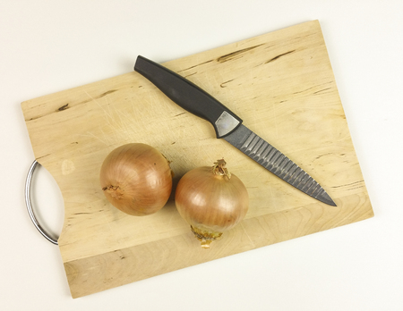 Onions on wooden chopping board on white background - top viewの写真素材