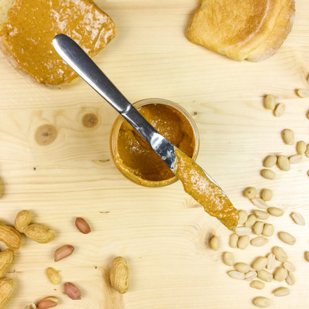 Peanut butter on a slice of bread in wooden background - top view