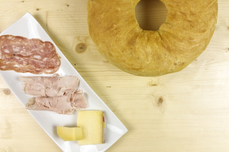 savory cake with salami, ham and cheese on wooden background - top viewの写真素材