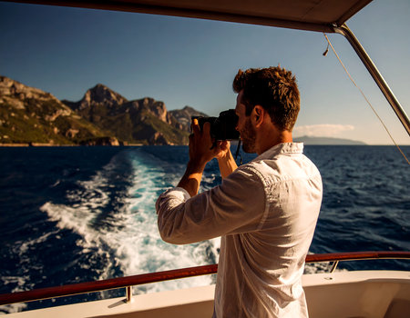 Young man taking photos of the sea with a camera on a yachtの素材