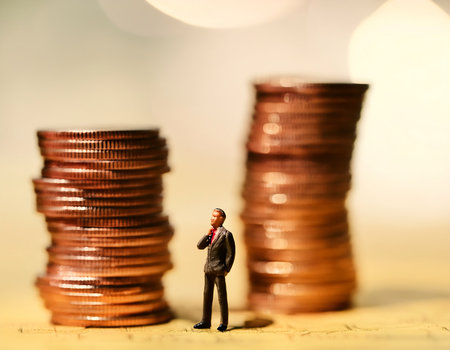 Miniature people : Businessman standing on stack of coins with bokeh background.の素材
