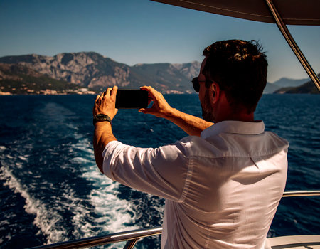 Man taking photo with smartphone on a yacht in the Mediterranean sea.の素材