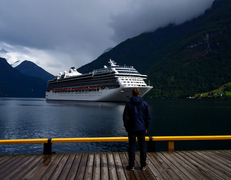 Young man looking at cruise ship on the fjord in Norwayの素材