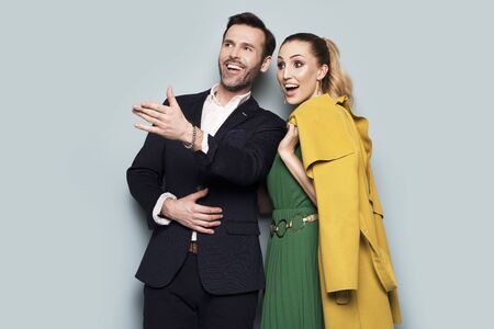 Joyful couple, elegantly dressed, standing on a blue backgroundの写真素材