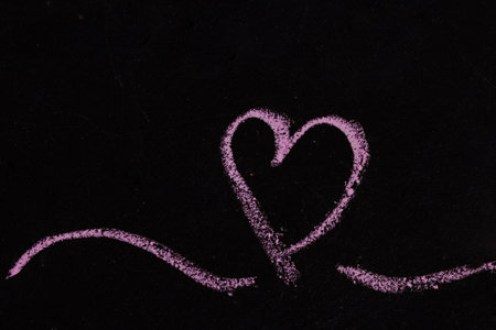 Drawing a heart on a blackboard with chalk. Valentine's day concept. The 14th of February.の写真素材