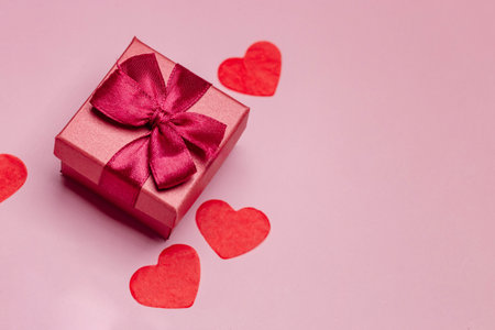 Paper art Valentines day concept banner with hand made gift box, paper cut ribbon, bow, and a lot of hearts on a red background with space for text.の写真素材