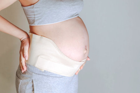 Pregnant woman belly in prenatal pregnancy maternity belt. Orthopedic abdominal support waist, back,...