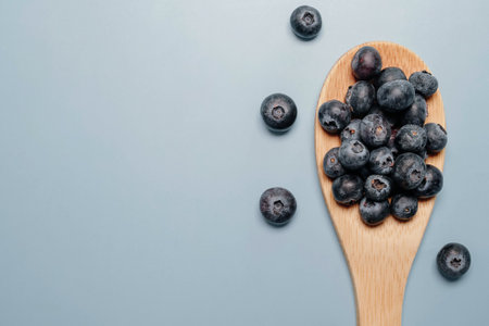 blueberries in a wooden spoon on a blue background. view from above. blueberry flatの写真素材