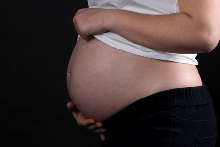 Pregnant Woman Belly. Pregnancy Concept. Isolated on Black Background. Pregnant tummy close upの写真素材
