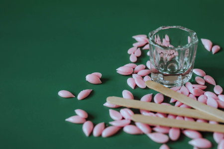 Materials for depilation of eyebrows. Pink wax granules on a green backgroundの写真素材
