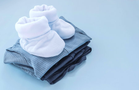 Clothes for a newborn boy lie in a pile on a blue background. Booties, overalls, suits.の写真素材