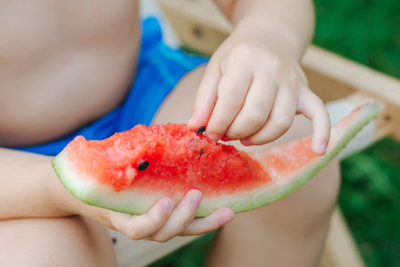 The child takes out the bones and the red watermelon. Summer vacation. Healthy Eatingの写真素材