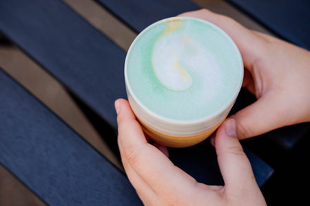 Coffee latte macchiato with mint syrup and whipped cream, on a wooden table of a summer cafe.の写真素材