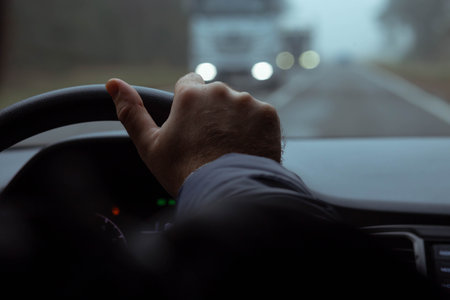 A driver driving a car driving on a foggy road in autumn.の写真素材