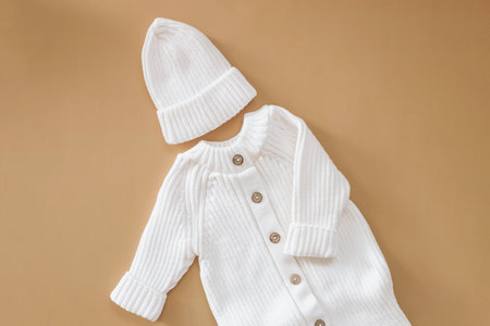 Knitted white jumpsuit for a newborn on a beige background. Outerwear for toddlers for walks in autumn or spring.の写真素材
