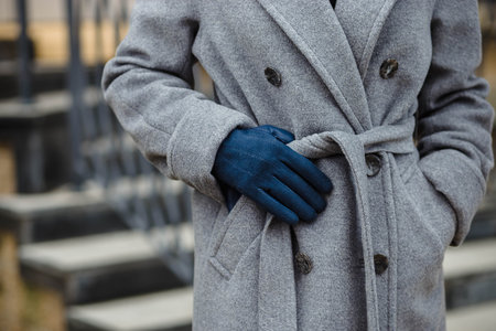 cropped shot of woman in wool coat tying belt.の写真素材